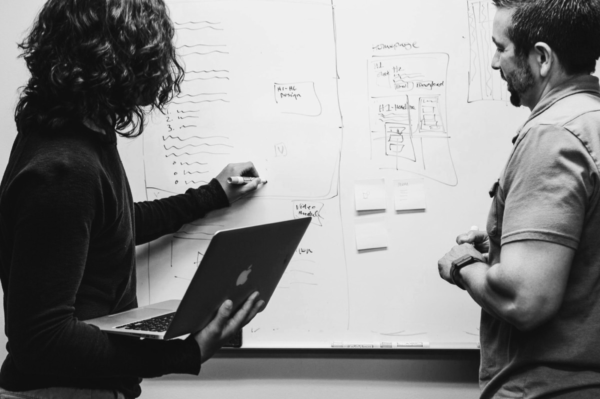 Two colleagues mapping a plan on a whiteboard