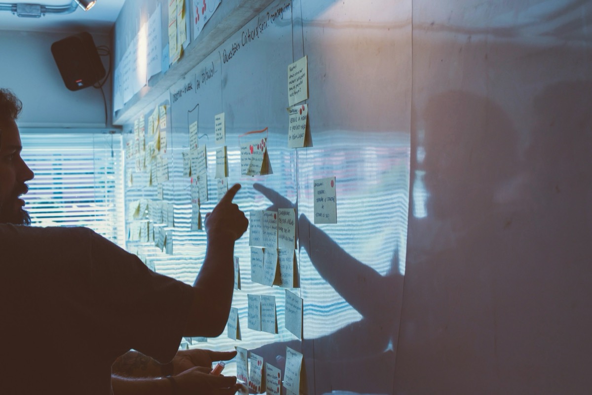 A team organizing sticky notes on a glass wall